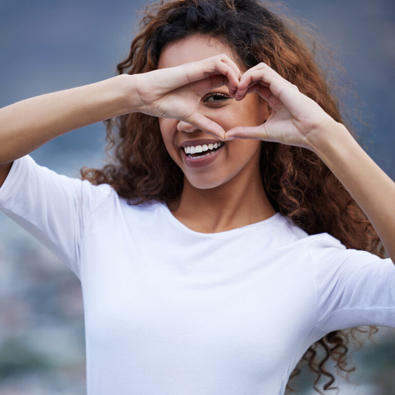Smiling woman making a heart shape with her hands, representing generosity and Legacy Giving through 6 Stones