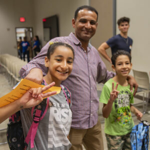 Family attends Operation Back 2 School with students receiving backpacks.