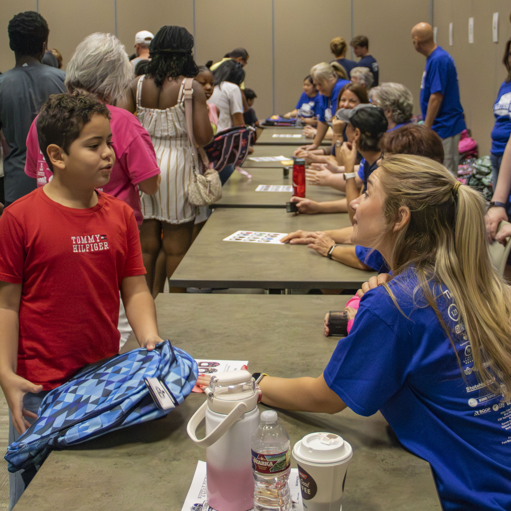 Volunteer gives a backpack to a student at Operation Back 2 School.