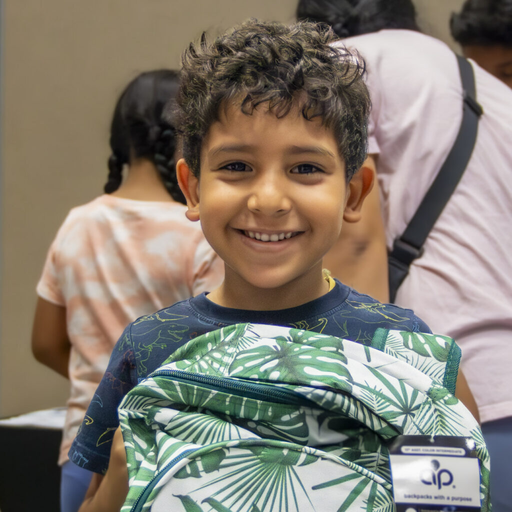 Student smiles with a backpack at Operation Back 2 School.