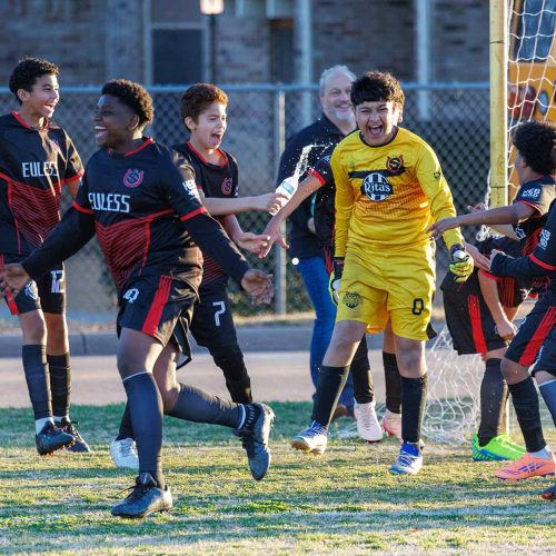 Liga HEB junior high soccer players celebrate together near the goal