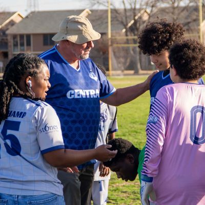 Liga HEB soccer volunteer encourages junior high players during a team huddle